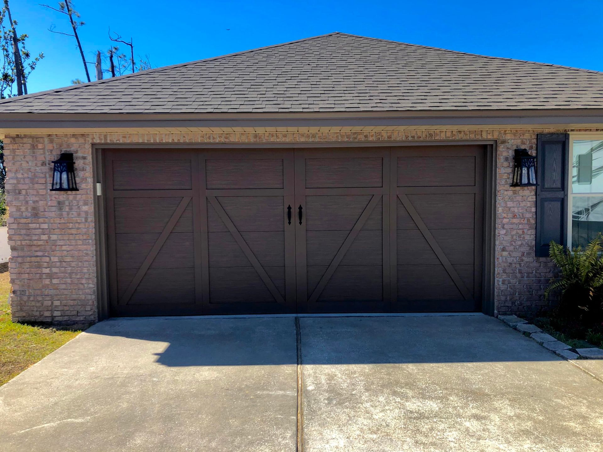 Single-car garage with brown double doors on a brick house, viewed from the driveway.