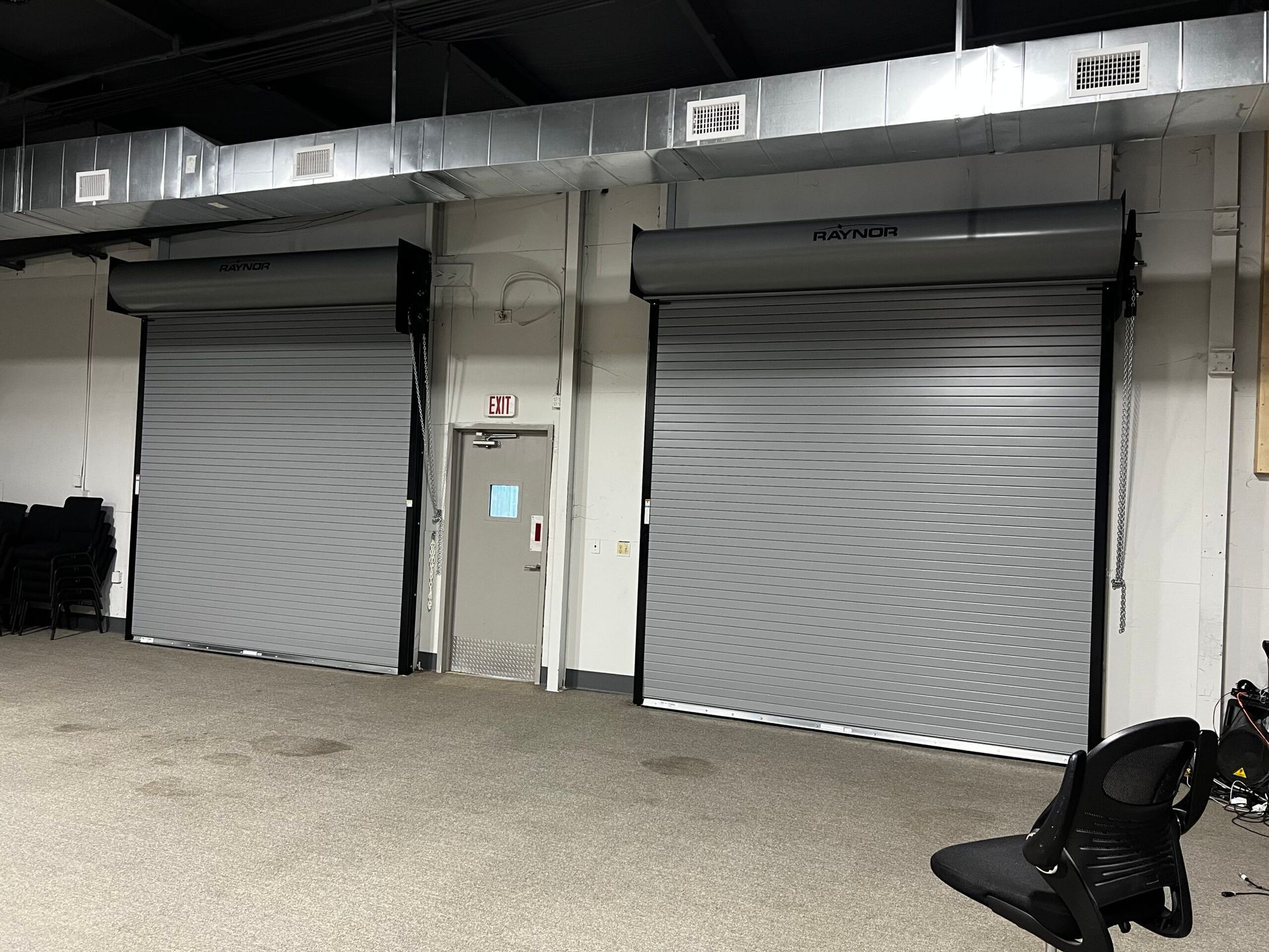 Two closed metal roll-up doors on a warehouse exterior at night