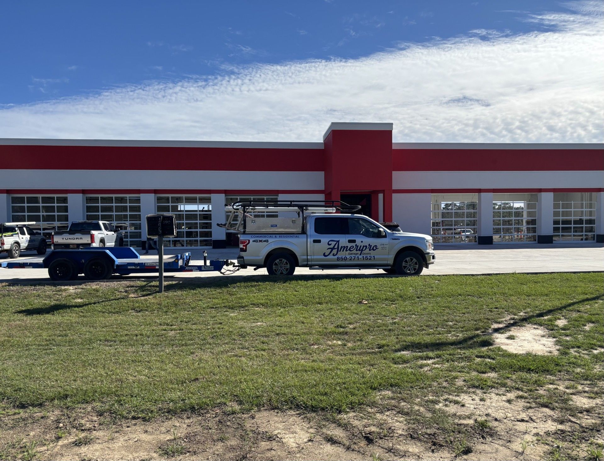 Parked service pickup trucks in front of a red-and-white commercial building.