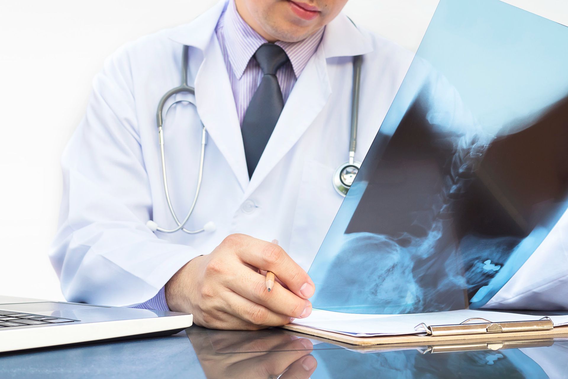 Doctor reviewing chest X-rays at a desk with a stethoscope and laptop