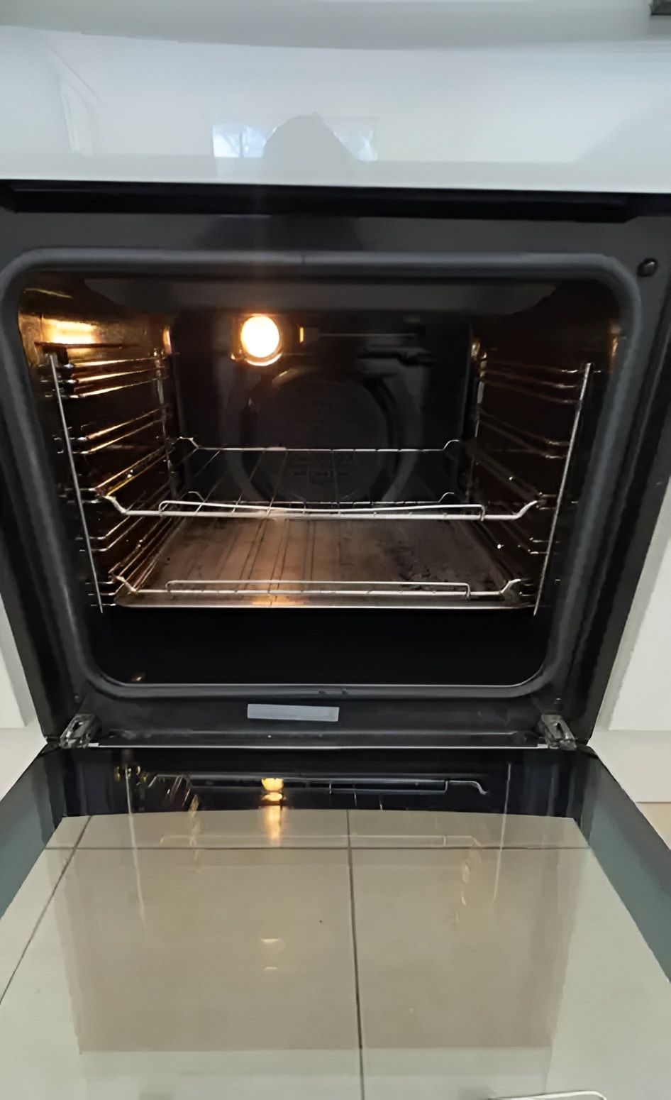 Opened Oven With Interior Racks and Light, Set Against White Tile Floor — Cleanaroo Property Services in Conder, ACT