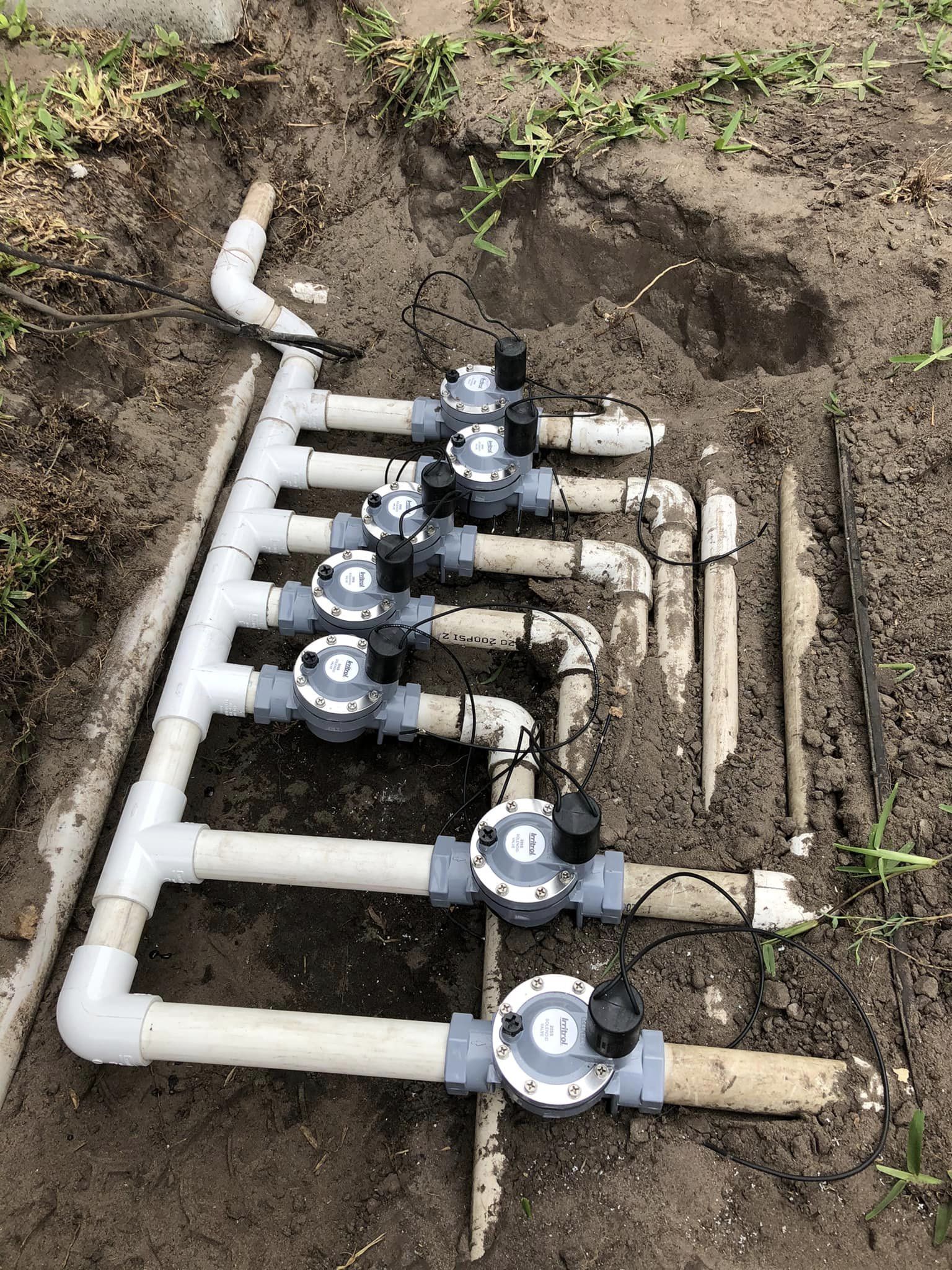 A row of water meters are sitting in the dirt.
