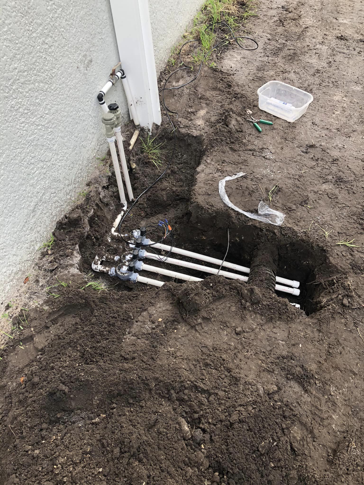 A hole in the ground next to a house with a hose coming out of it.