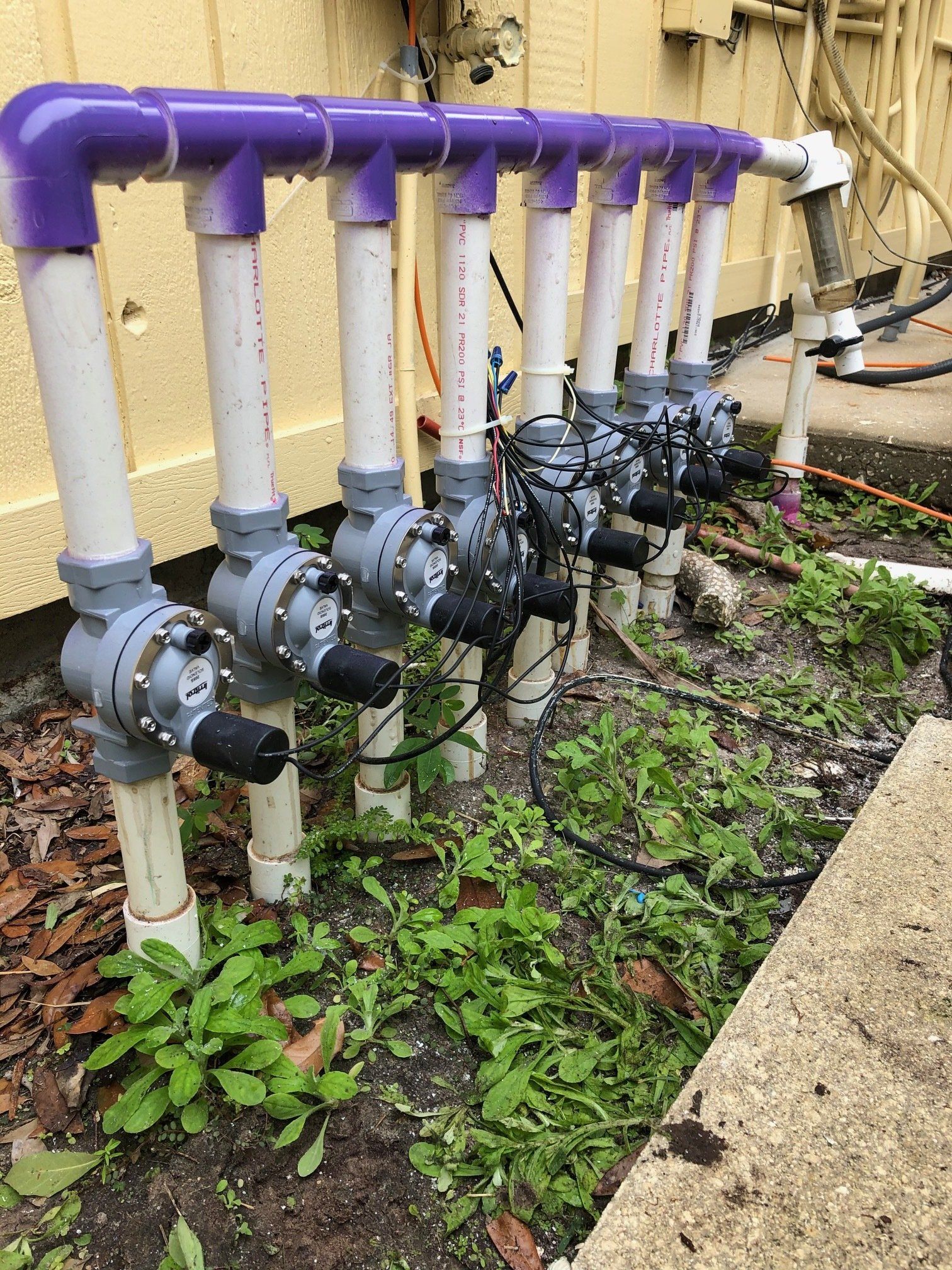 A row of purple and white pipes sitting next to each other on the ground.