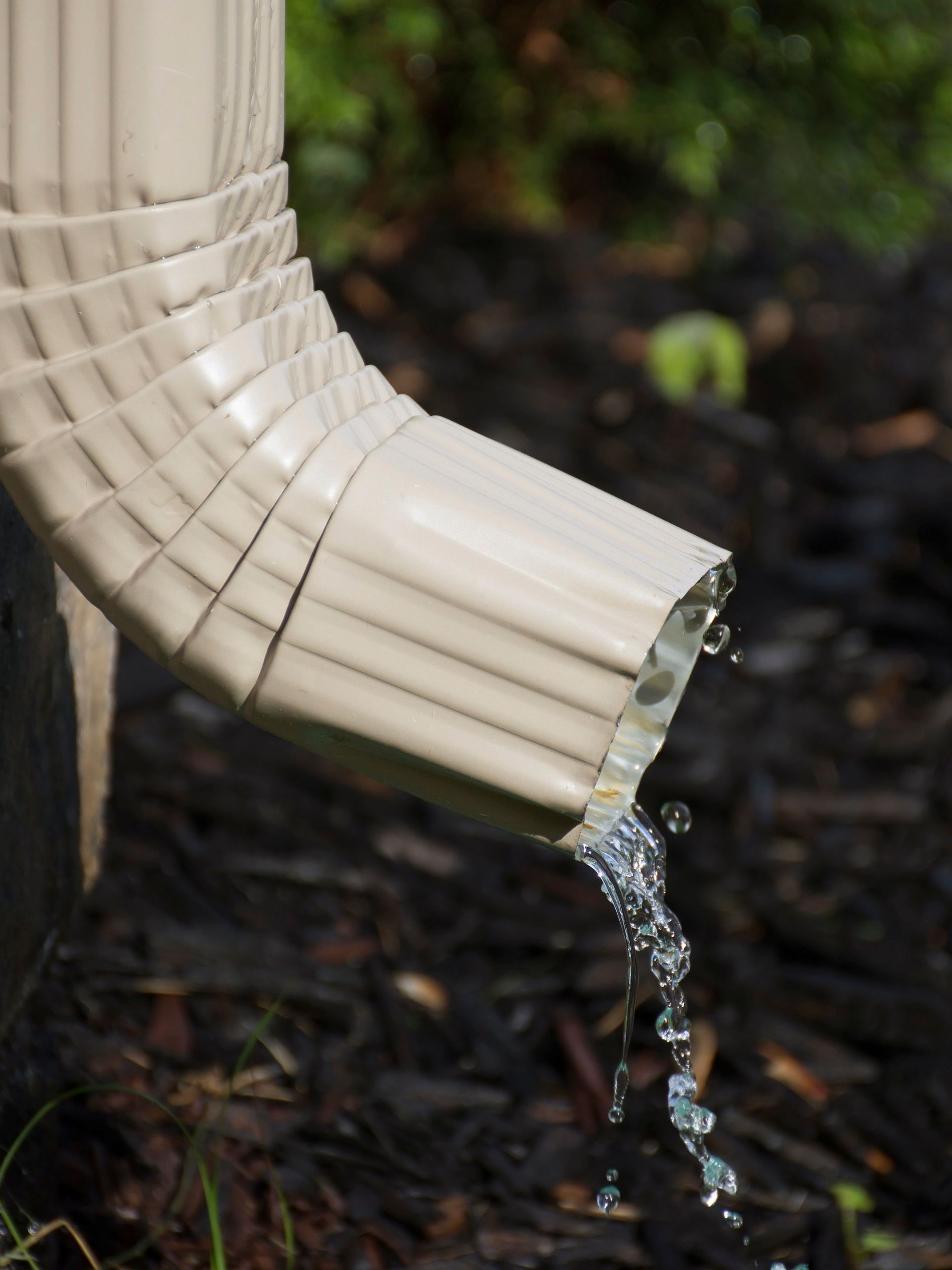 A close up of a gutter with water coming out of it.