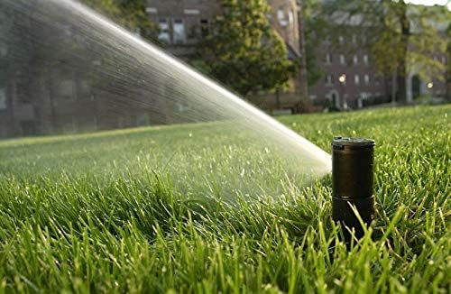 A sprinkler is spraying water on a lush green lawn.