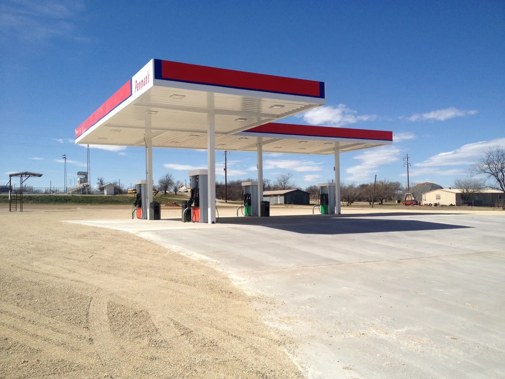 Gas station with red and white canopy; blue sky.