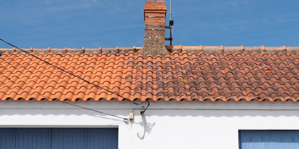 A White House With A Red Tiled Roof And A Chimney — Topflite Roofing In Vincentia, NSW