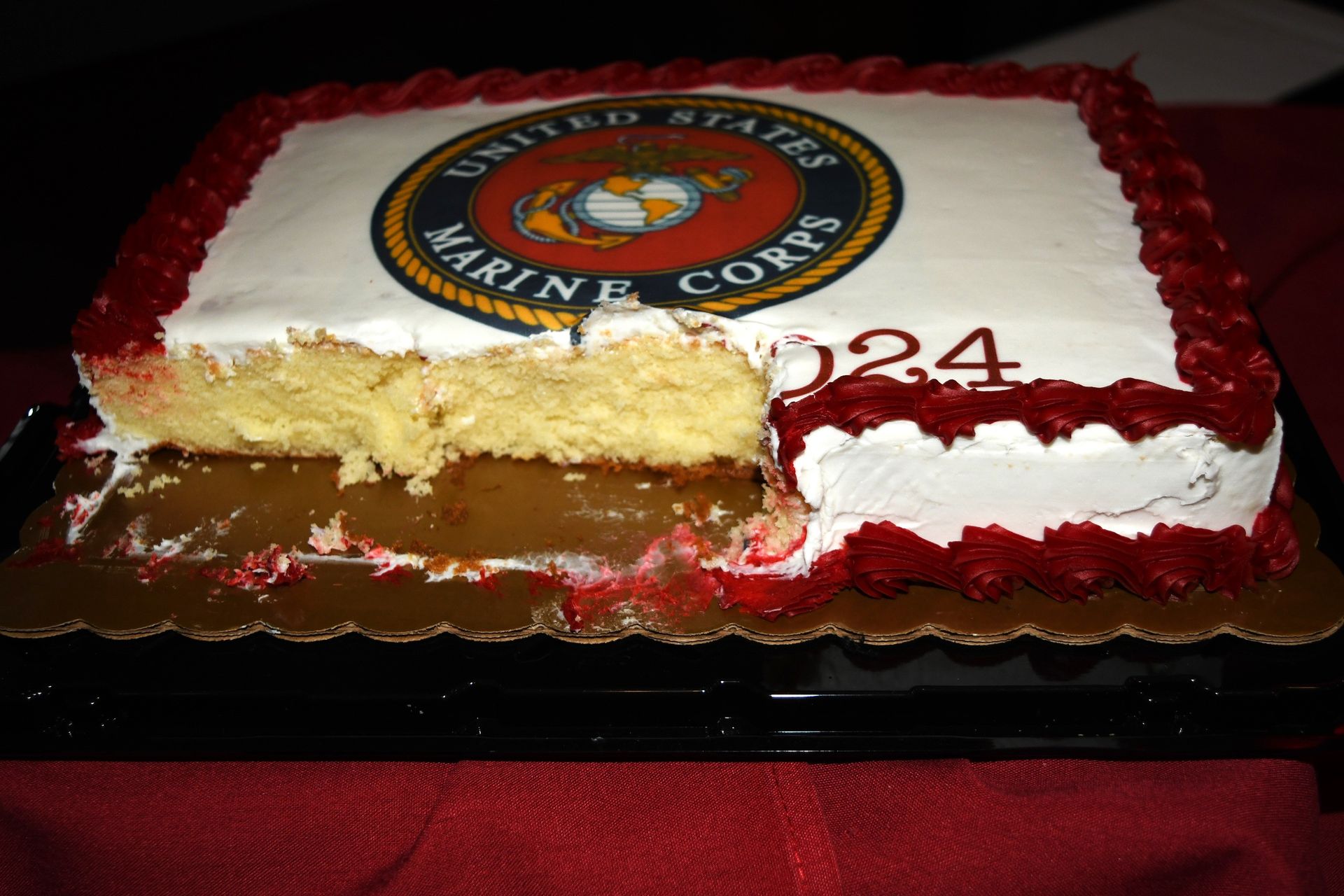 Marine Corps cake with a slice cut out, red and white frosting, and a logo on top