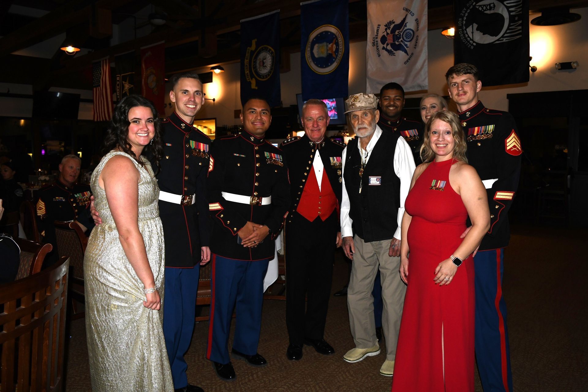 Group of people in formal attire posing at an event, with military uniforms and evening gowns, holding awards.