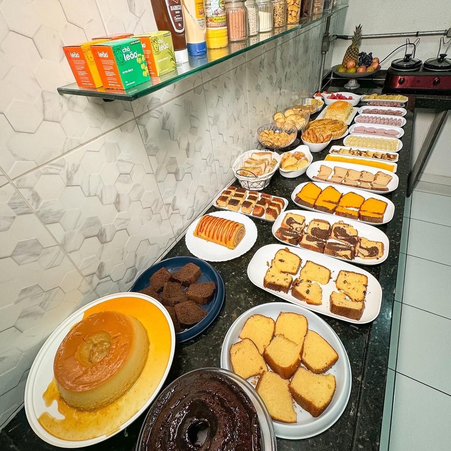 Uma mesa de bufê exibindo uma variedade de bolos, doces e condimentos.