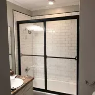 Bathroom shower with black-framed glass doors and white subway tile walls.