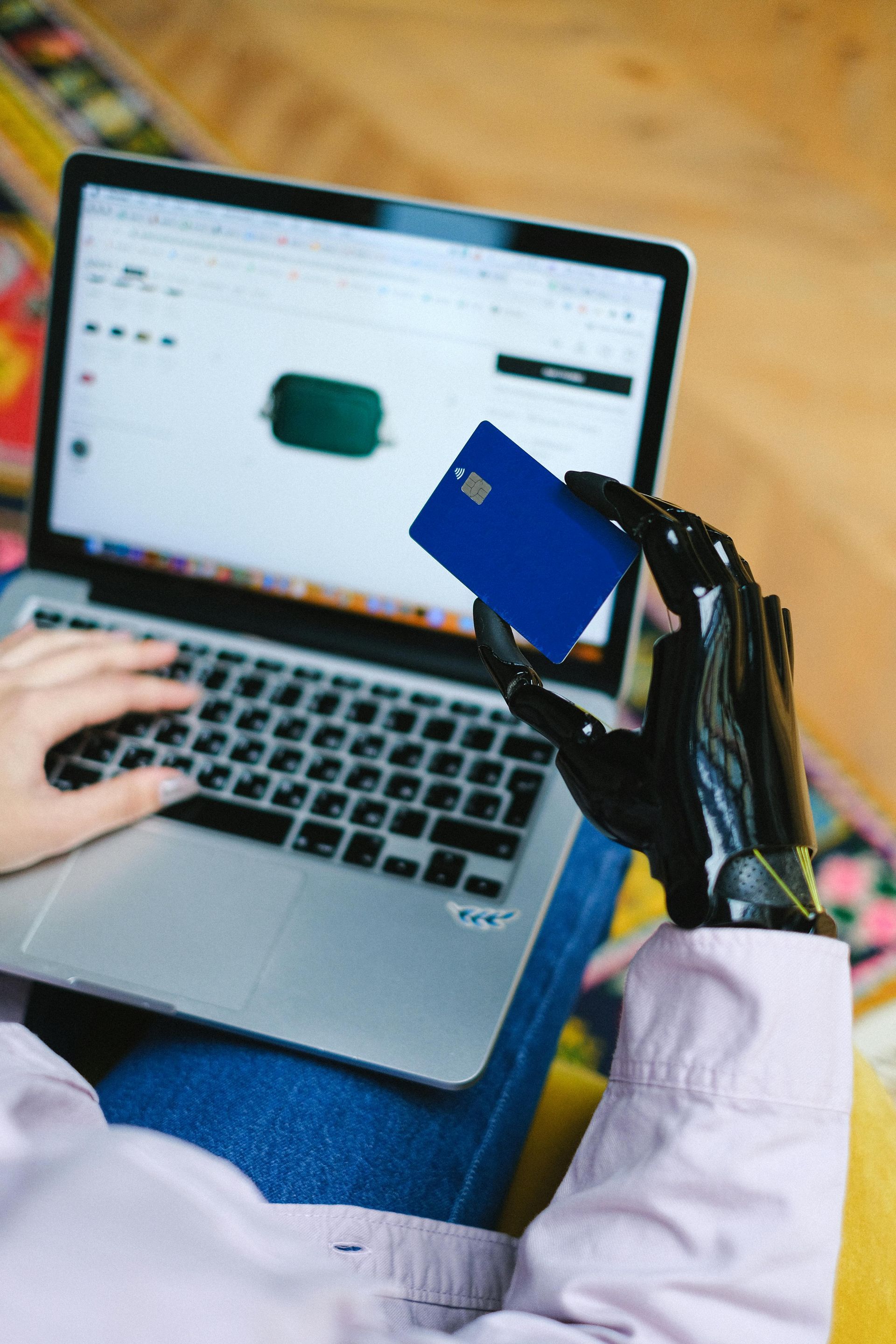 A person is using a laptop and holding a credit card.