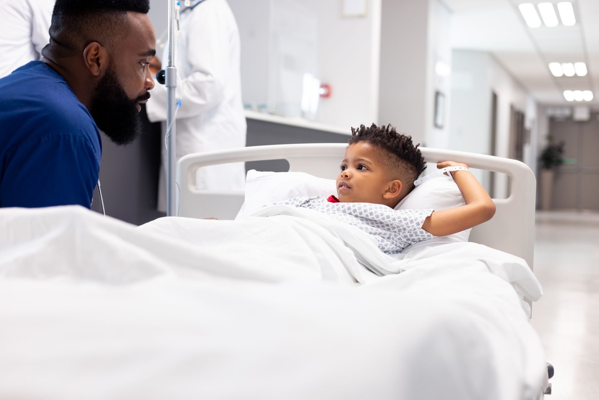 A man is talking to a young boy in a hospital bed.