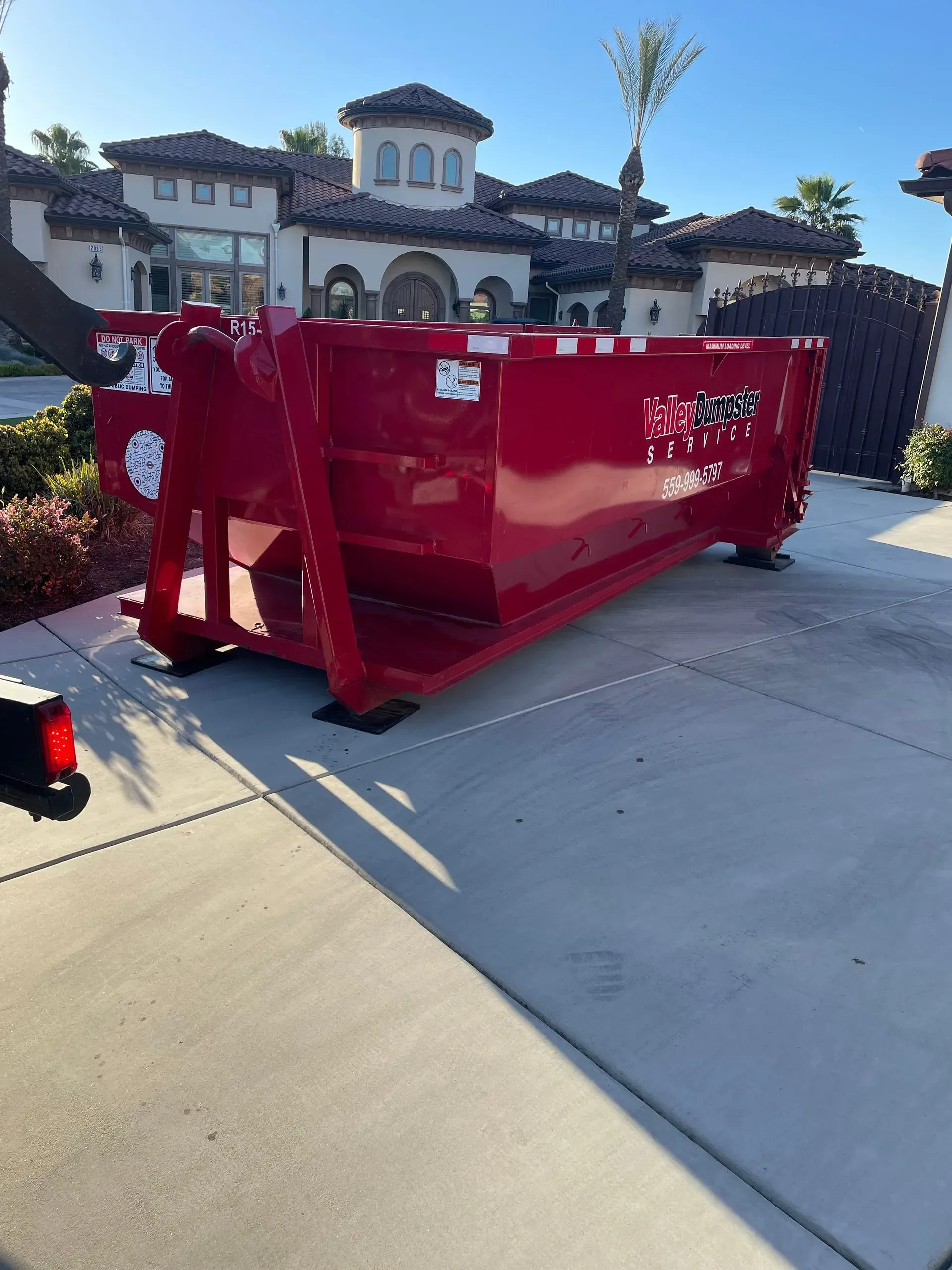 Valley Dumpster Service delivery — red dumpster placed on residential driveway in Fresno