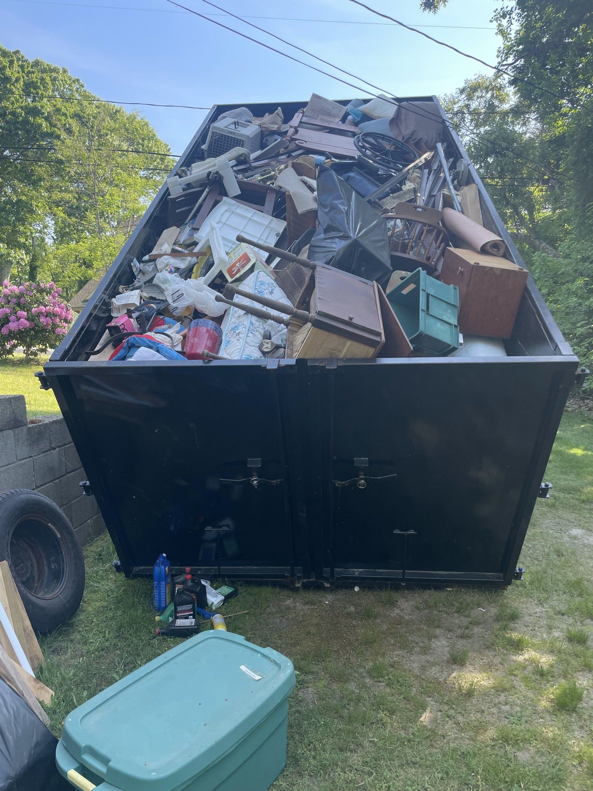 full dumpster with broken furniture and garbage