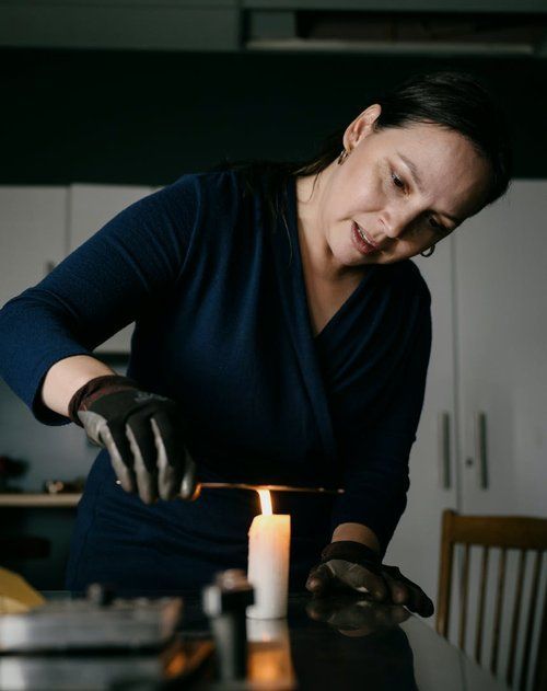 A woman in a blue dress is lighting a candle on a table.