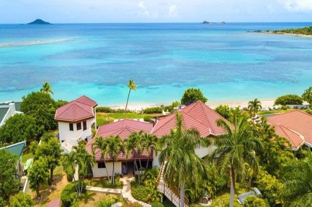 Tropical beachfront resort with red-roofed villas and palm trees at Caribbean Wind villa