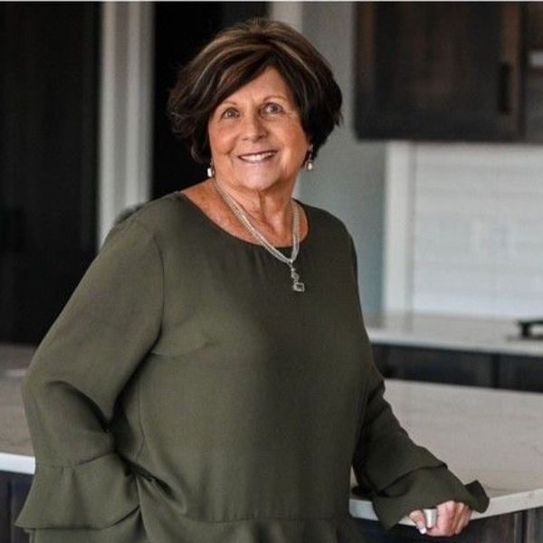 Woman in an olive green top smiling in a modern kitchen