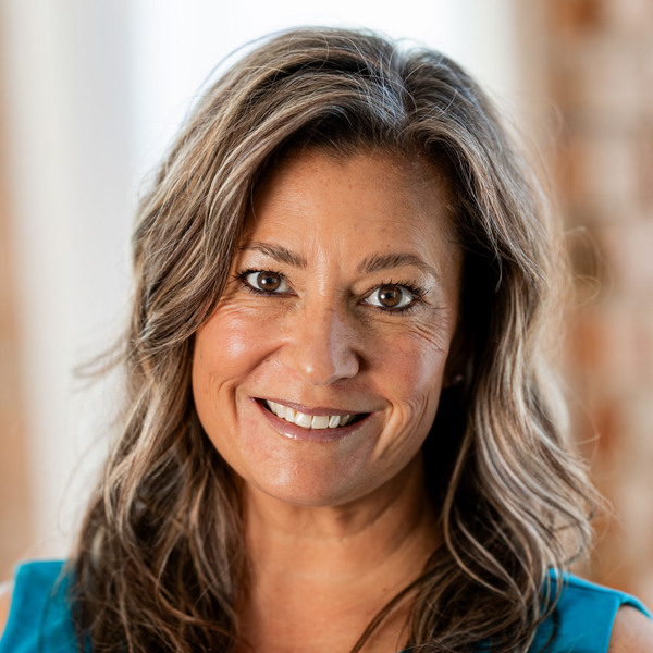 Smiling woman in a turquoise top, facing the camera against a softly blurred background
