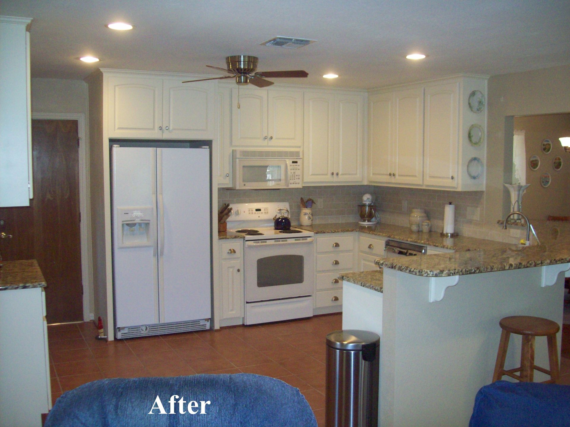 A kitchen with white cabinets and granite counter tops is shown after being remodeled