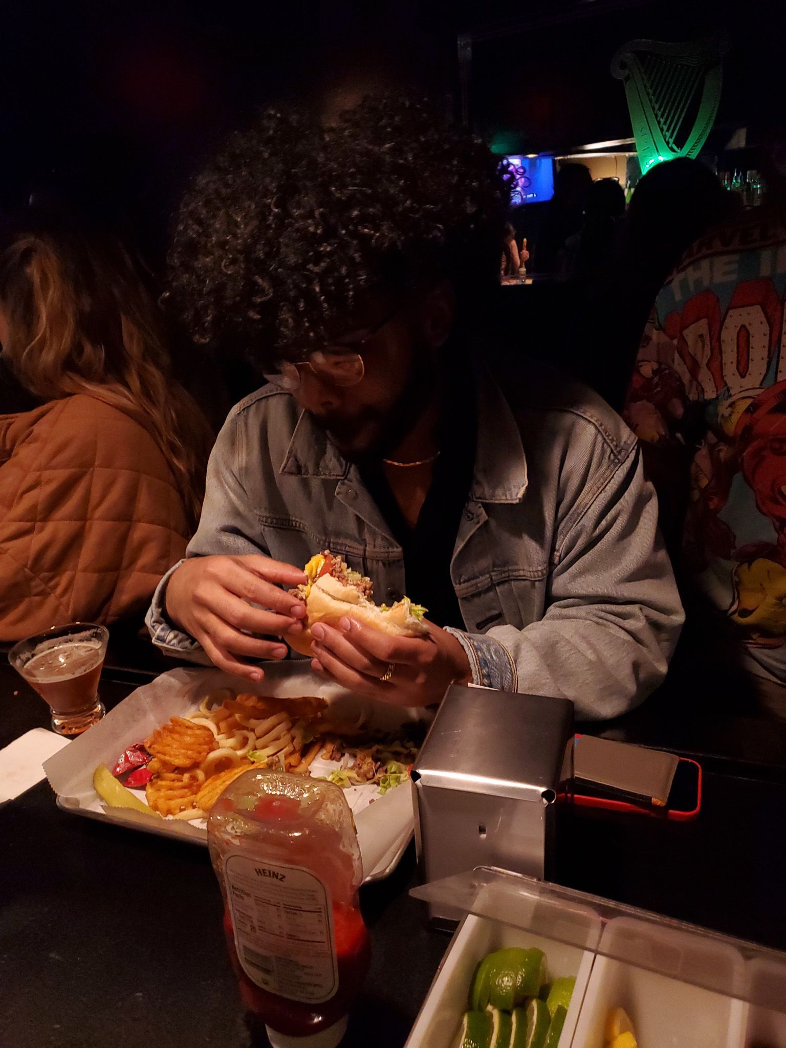 A young adult sits eating a chopped cheese at bad ending, a bar in rochester ny