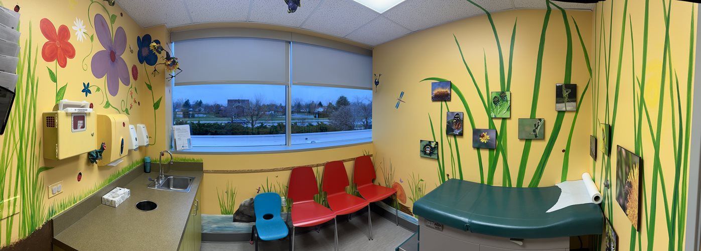 Bright classroom with yellow walls, colorful chairs, green tables, and a large window overlooking water