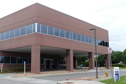 Brick office building with covered entrance and large upper windows on a street corner