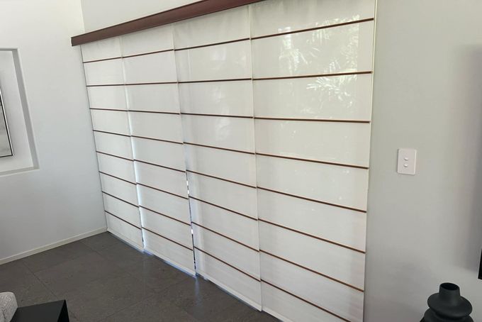 A Living Room With A Sliding Glass Door Covered In White Blinds — Advantage Screens and Blinds Hervey Bay In Pialba, QLD