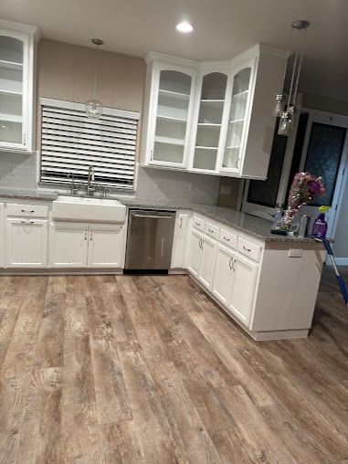 White kitchen cabinets and counters, stainless steel appliances, and wood-look flooring.