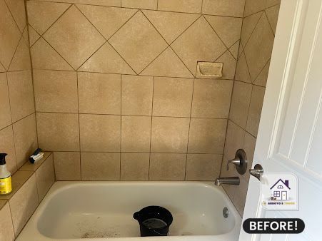 Bathroom with tiled walls, bathtub, soap dish, and open white door;