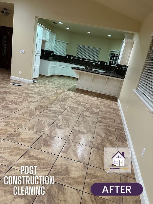 Post-construction kitchen after cleaning. Beige floor tiles, white cabinets, black countertops.