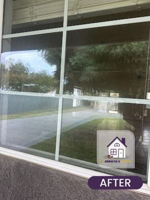 Cleaned window with outside view, reflecting trees, grass, and a driveway.