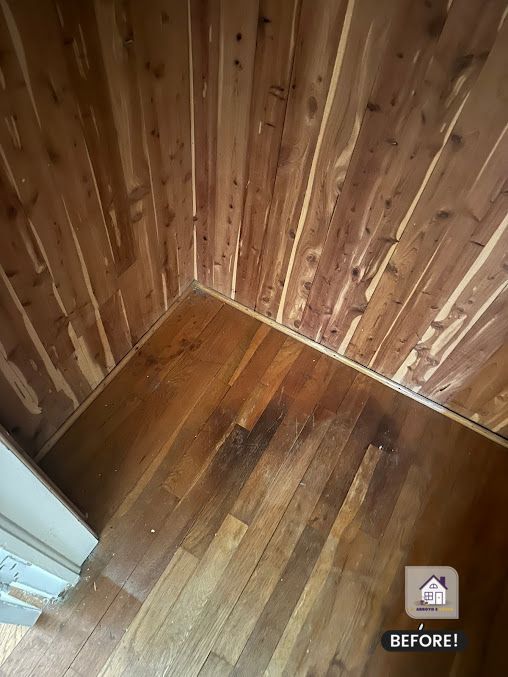 Corner of a room with cedar plank ceiling and hardwood floor, dark wood tones.