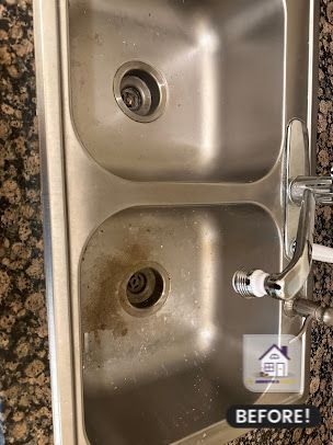 Stainless steel kitchen sink with brown stains in one basin; faucet is visible.
