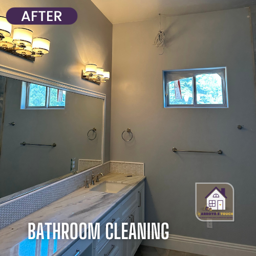 Bathroom with gray walls, white cabinets, marble countertop, large mirror, and three light fixtures.