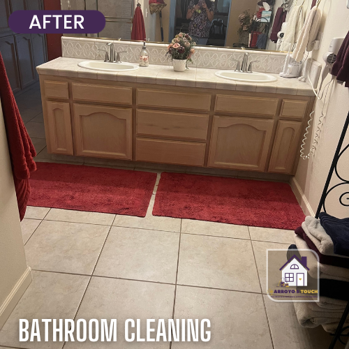Bathroom with double vanity, red rugs, beige tile floor.