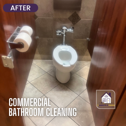 Clean commercial bathroom with a toilet and brown wood stalls.