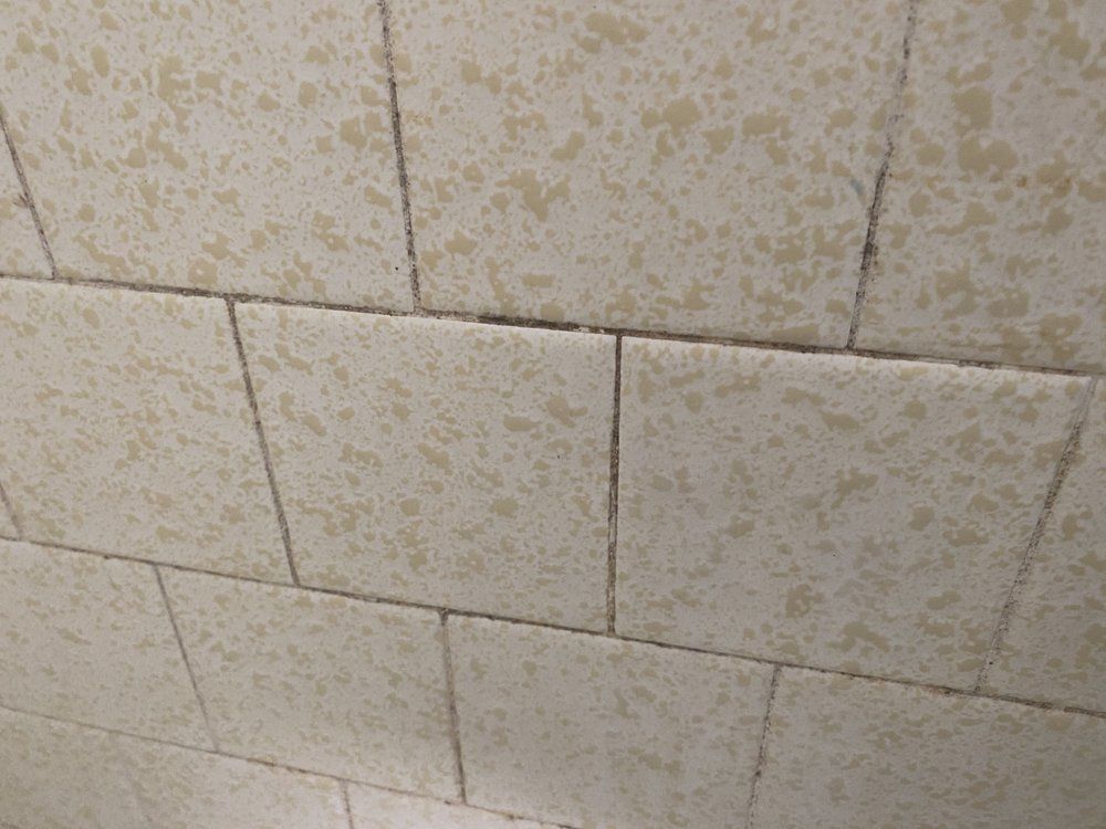 Cream-colored tiles with dark grout lines, angled view, close-up.
