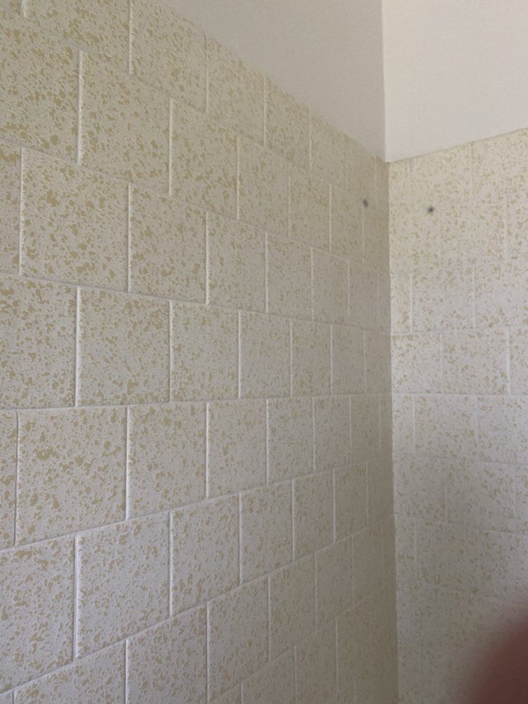 Tan, textured wall tiles in a corner, beneath a white ceiling.
