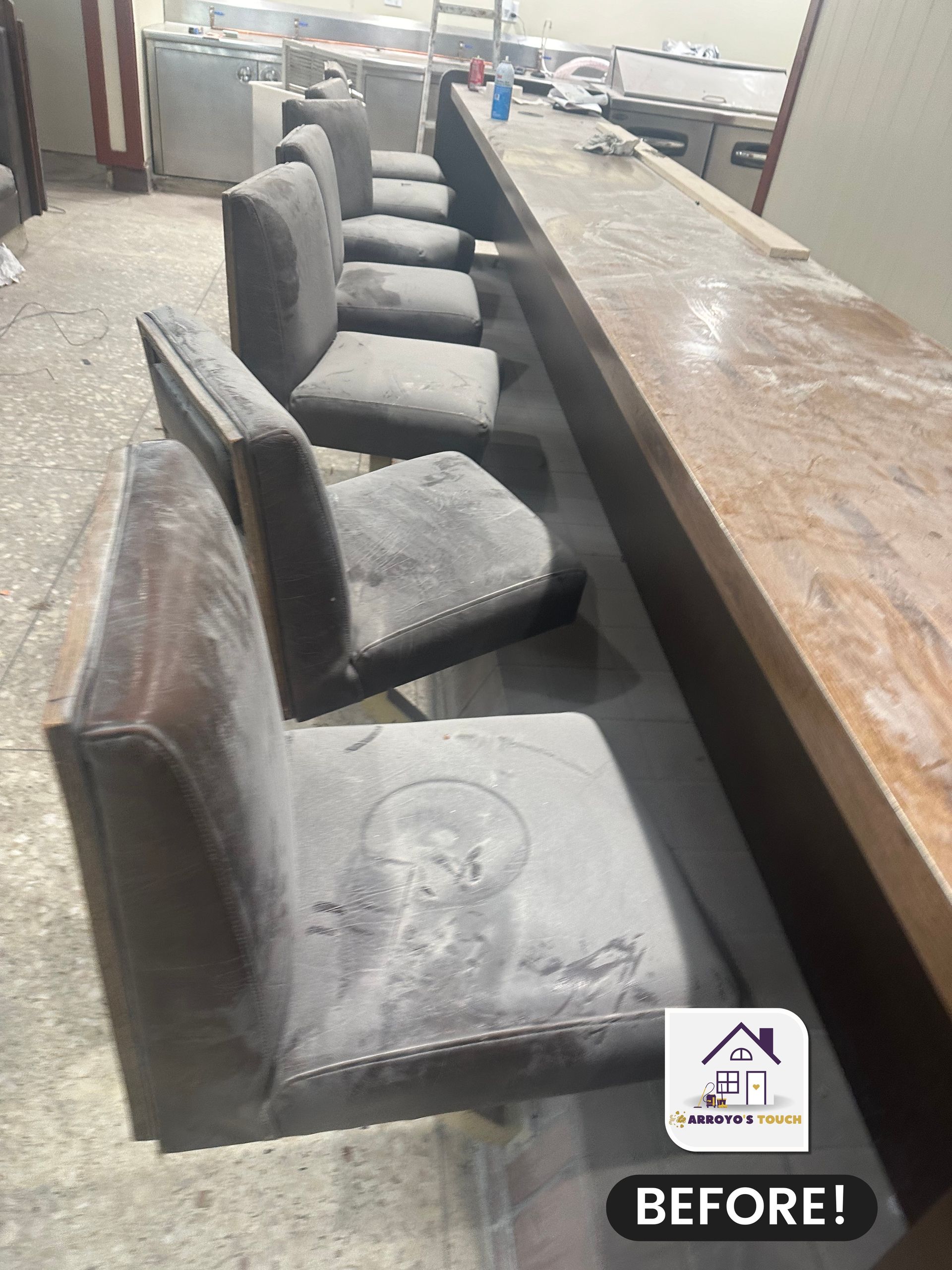Bar with dusty, gray upholstered stools, a long wooden counter, and a 