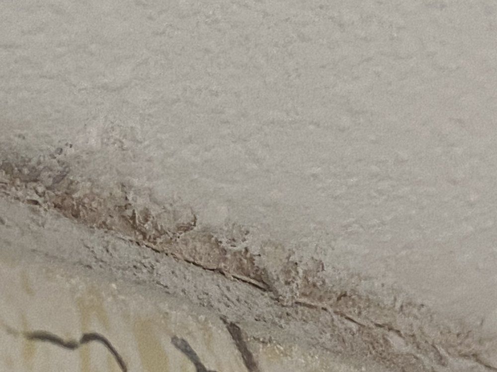 White, textured wall with a horizontal crack and light brown discoloration at the edge.
