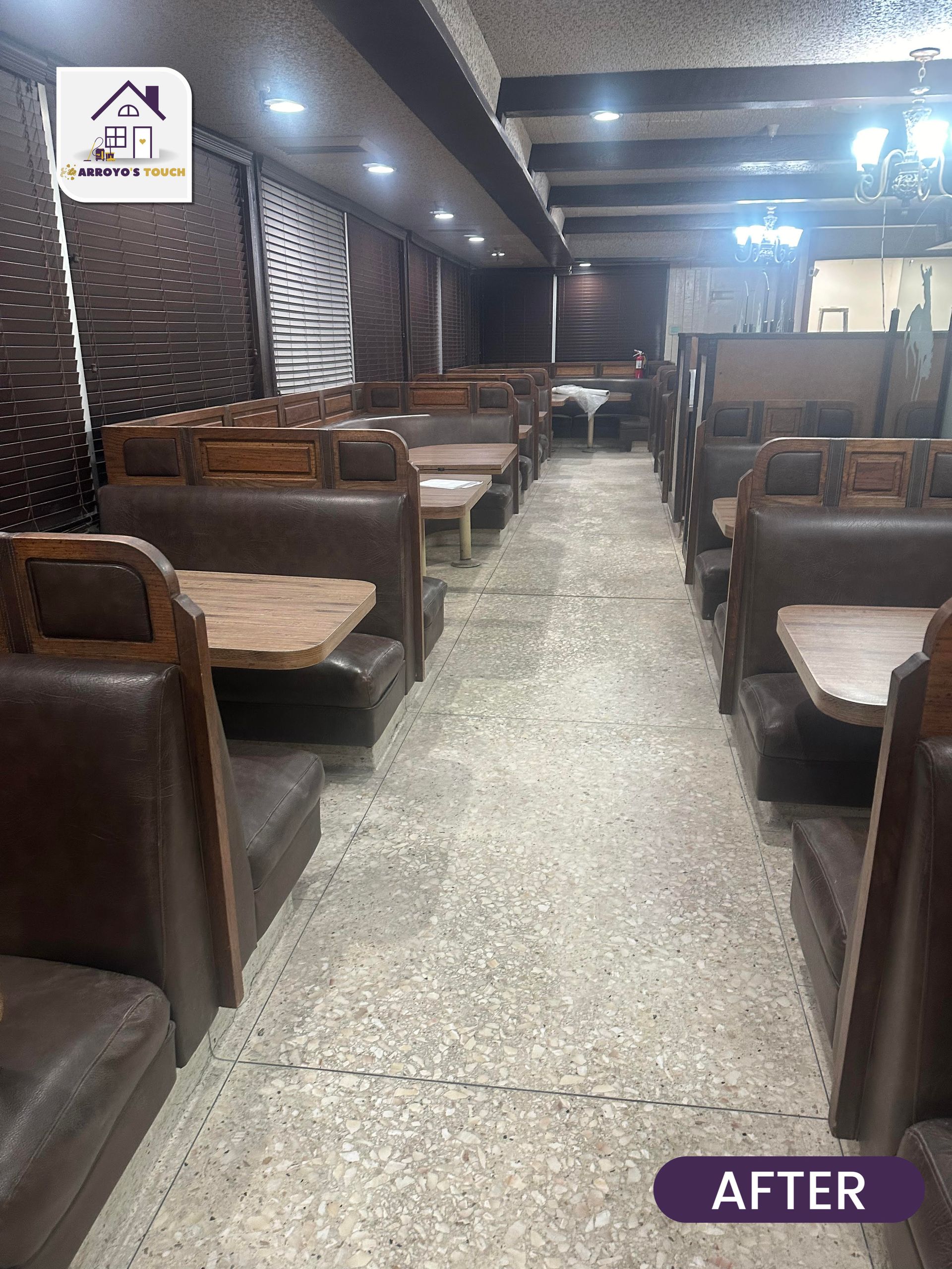 Restaurant interior with brown booths and tables, a central aisle, and dim lighting.