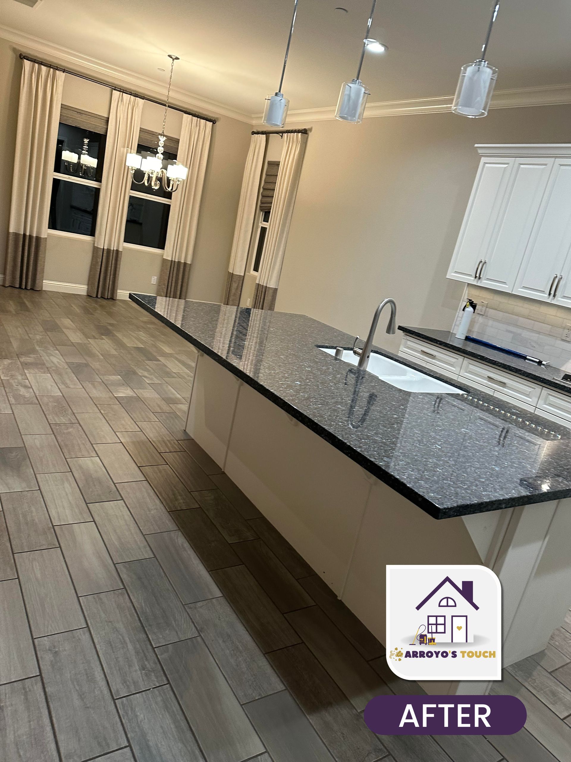 Kitchen with gray flooring, a large island with a speckled countertop, and white cabinets.