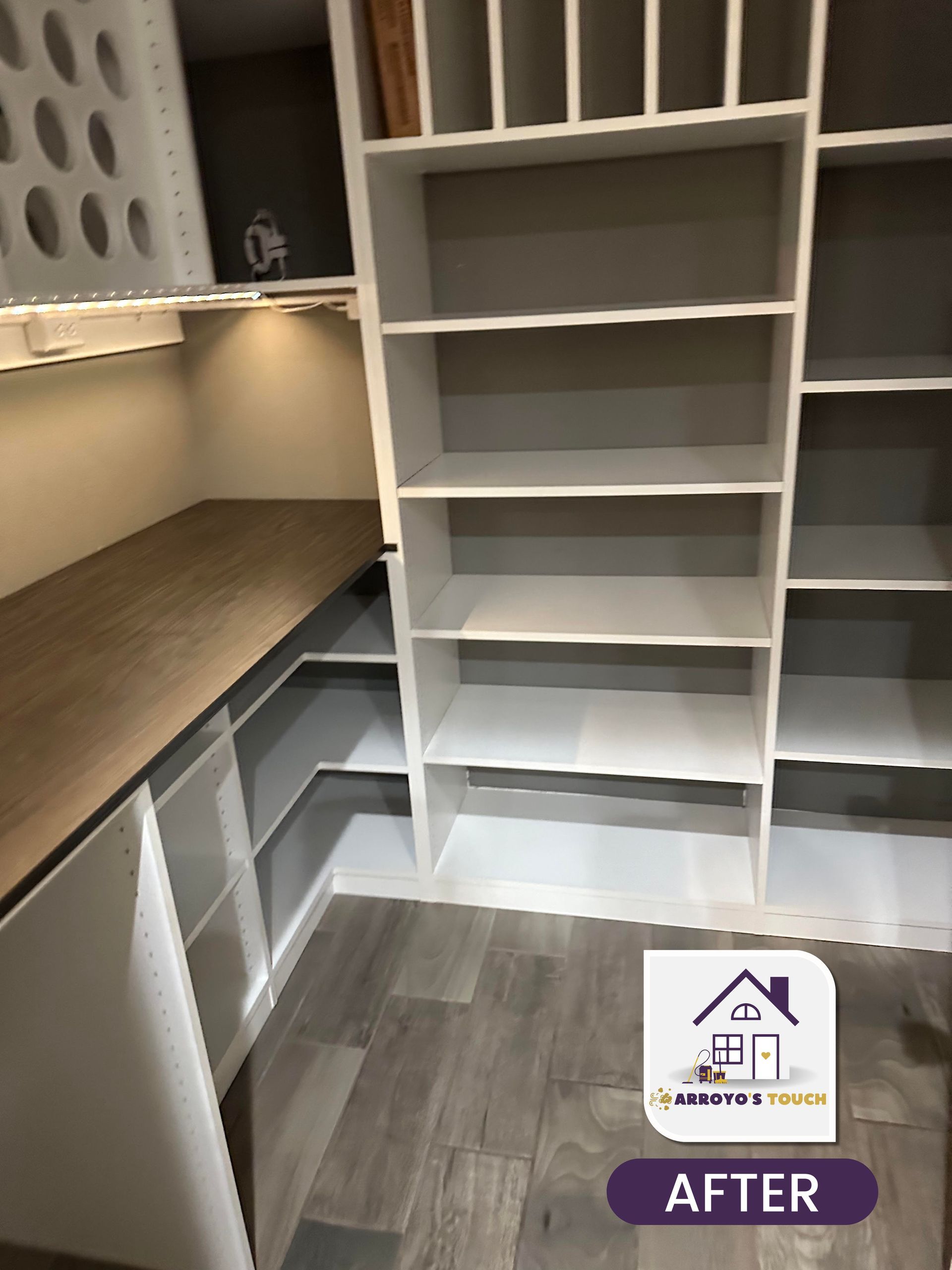 White built-in shelving and counter in a renovated room with wooden floors.