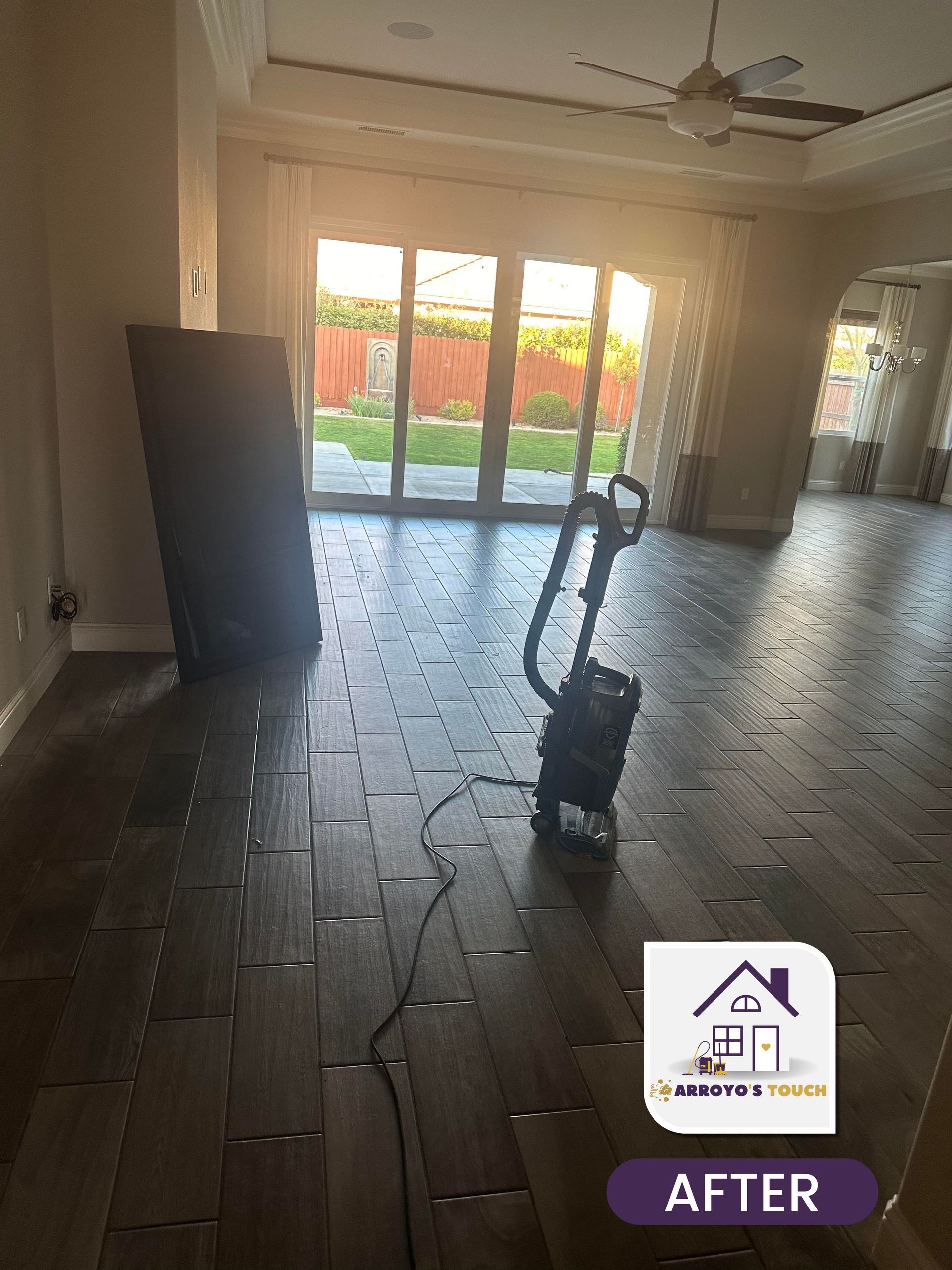 Living room with new wood-look tile flooring. A cleaning machine sits on the floor near a sliding glass door.