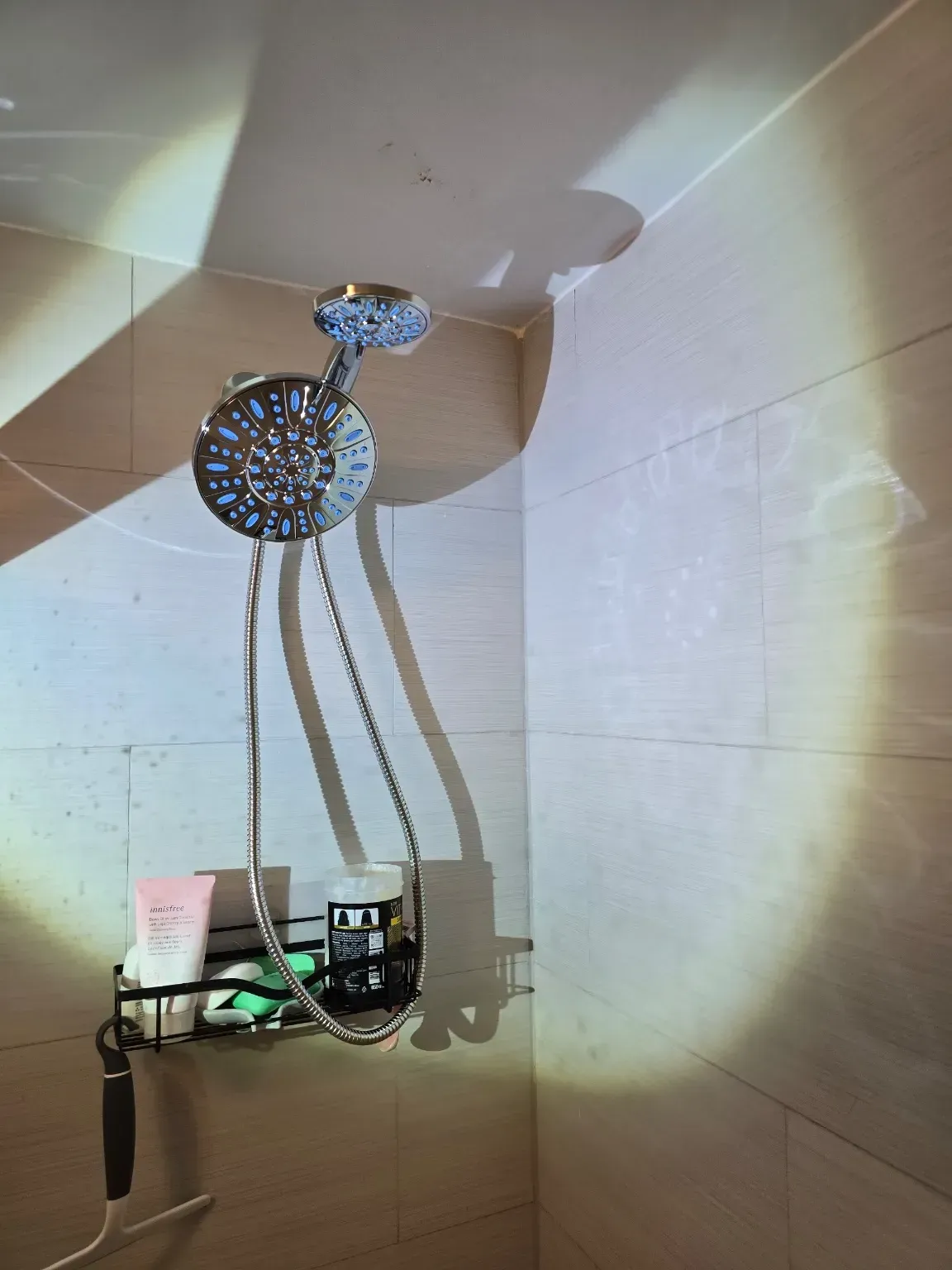 A shower head is hanging from the ceiling in a bathroom.