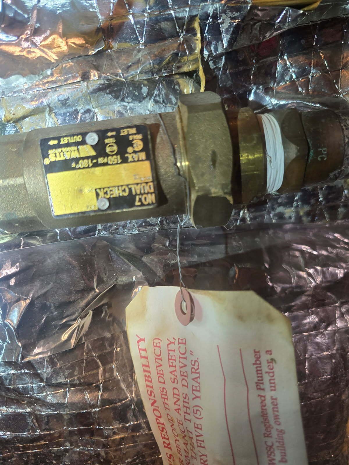Yellow-labeled industrial valve with attached tag, resting on crinkled plastic packaging.
