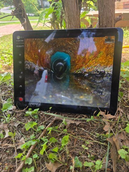 Tablet on grass showing a scenic outdoor video with autumn trees and water