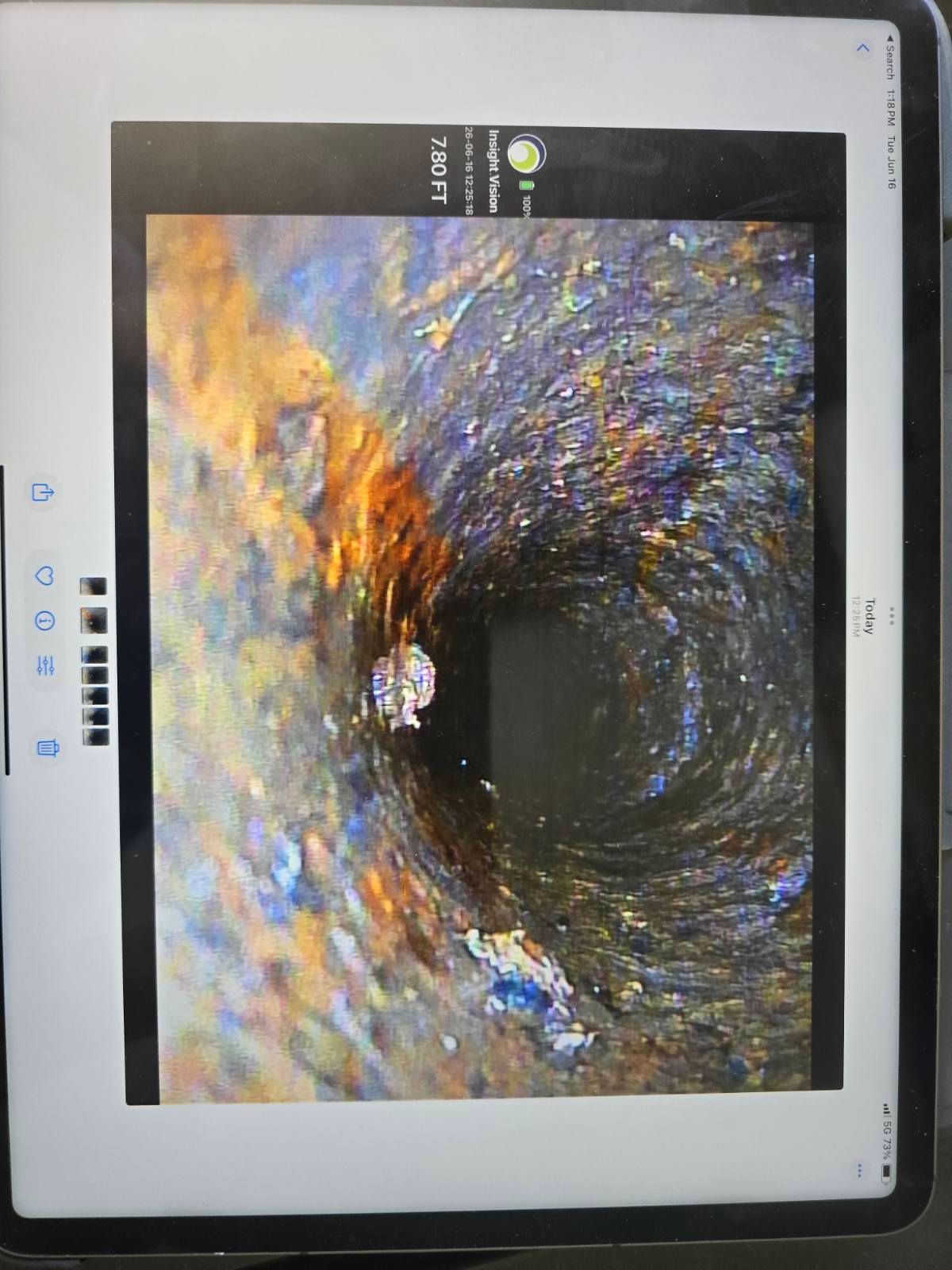 Endoscopic view inside a tubular passage with orange debris and dark center, shown on a medical monitor